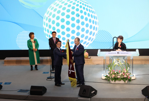 OC연합회 한성준 신임회장이 김도영신임이사장과 이임하는 민김 권사가 지켜보는 가운데 이임하는 신용회장으로 부터 회기를 받아들고 있다