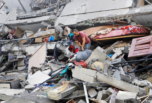 지난 10월8일, 팔레스타인 주민들이 이스라엘의 가자 시티 공습에 의해 파괴 된 와타나 타워의 폐허를 둘러보고 있다.